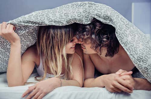 Pareja en la cama mirándose de frente previendo las enfermedades de transmisión sexual (ETS)