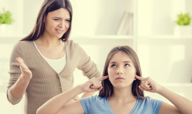 Adolescente mostrando reactancia y no escuchando a su madre