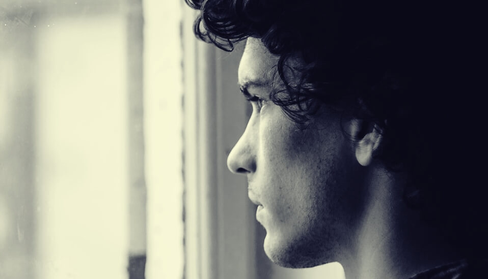 chico mirando por ventana representando a los hijos adultos de madres controladoras