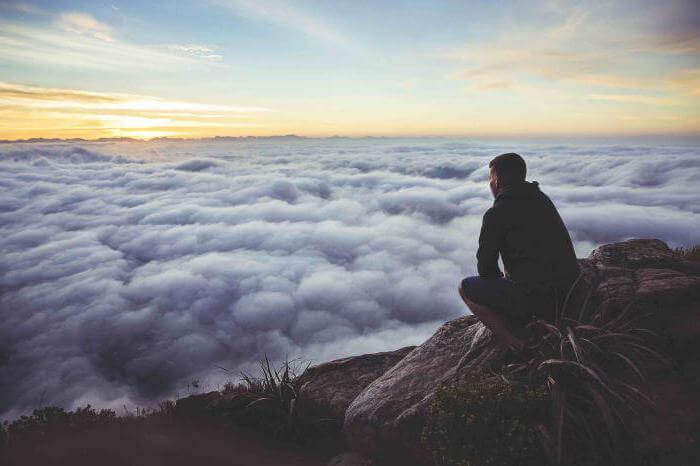 Hombre en la montaña pensando en la esperanza y perseverancia