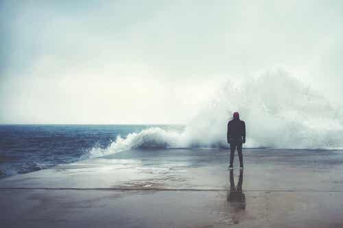 Hombre mirando una ola en el mar pensando en los ingredientes de la felicidad