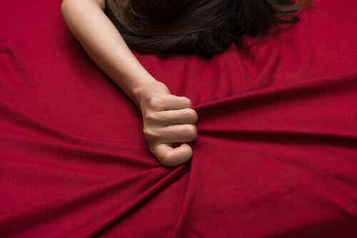 Mujer agarrando sábanas rojas de la cama