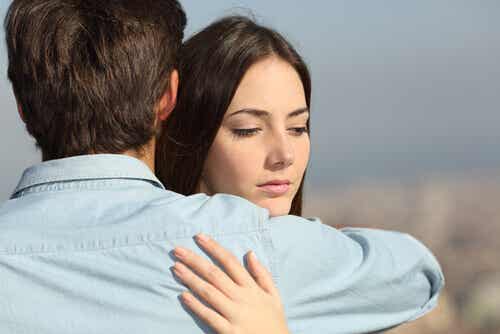 Vrouw knuffelt haar partner en denkt aan een andere man