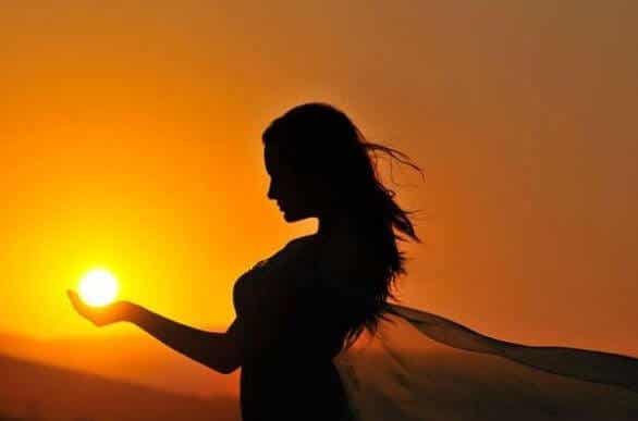 mujer sujetando sol en la mano representando las frases para recuperar la energía positiva