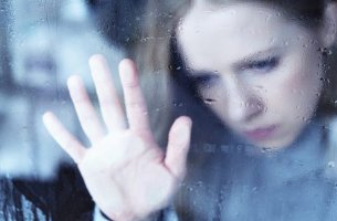 Mujer tras un cristal con lluvia