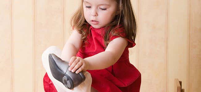 niña autónoma poniendose un zapato y representando las frases de María Montessori