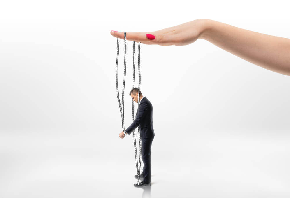 Mano sujetando la marioneta de un hombre