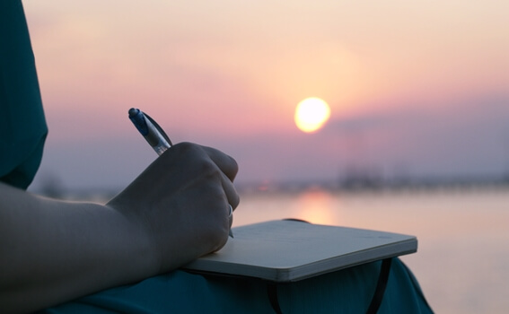 mujer escribiendo al amanecer simbolizando el arte de expresar el dolor emocional