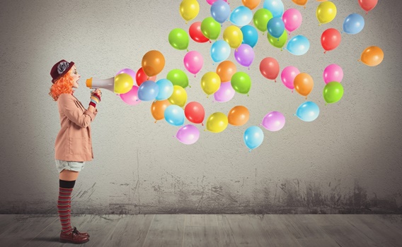 mujer payaso con megáfono del que salen globos haciendo el ridículo