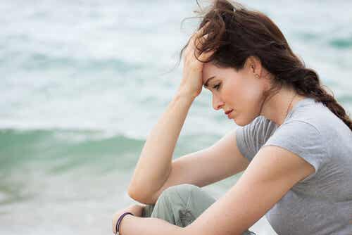 Mujer sentada frente al mar pensando que la vida es difícil