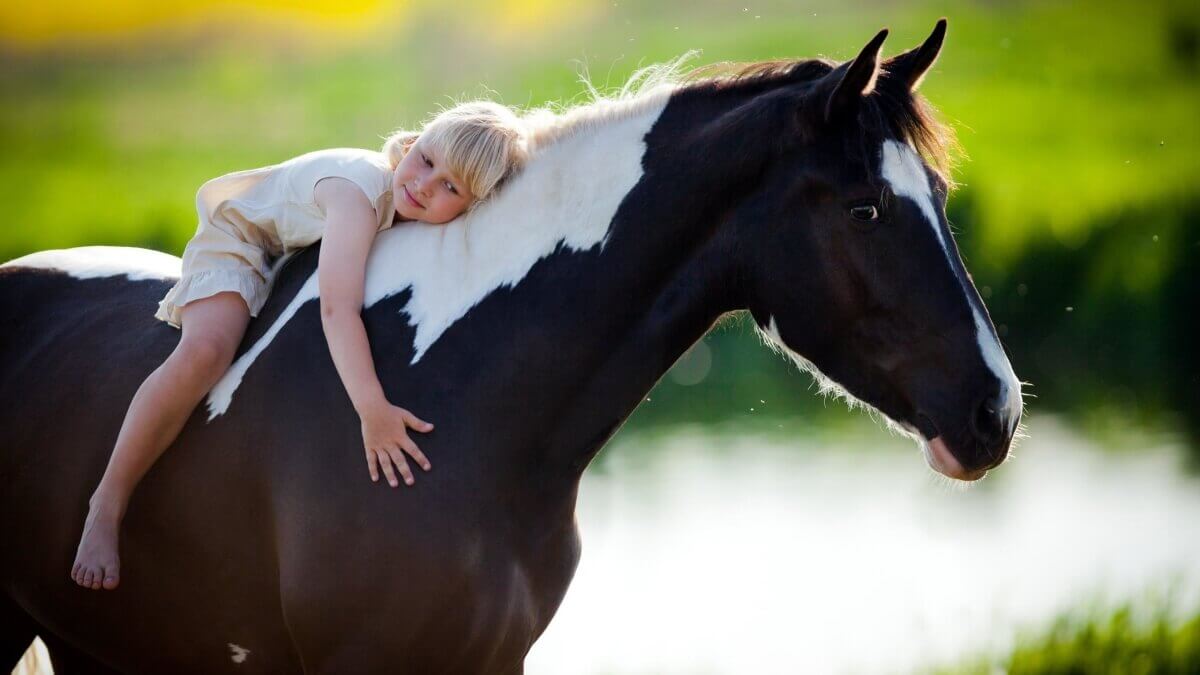 Niña abrazada a caballo
