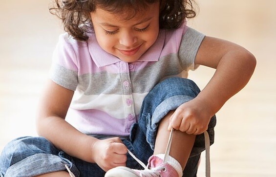 niña atándose zapatos representando el acto de ser perseverantes
