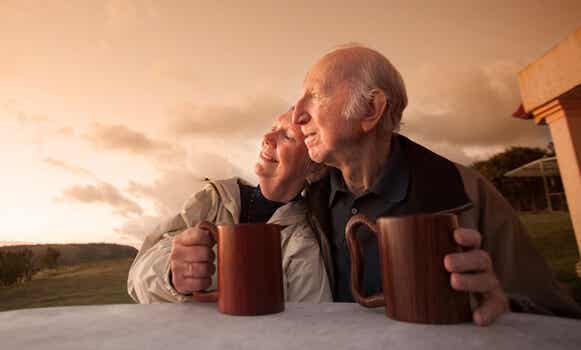 pareja mayor tomando algo al atardecer felices por envejecer saludablemente