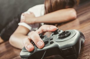 Adolescente en el suelo con un mando de la videoconsola para representar el trastorno de juego por internet