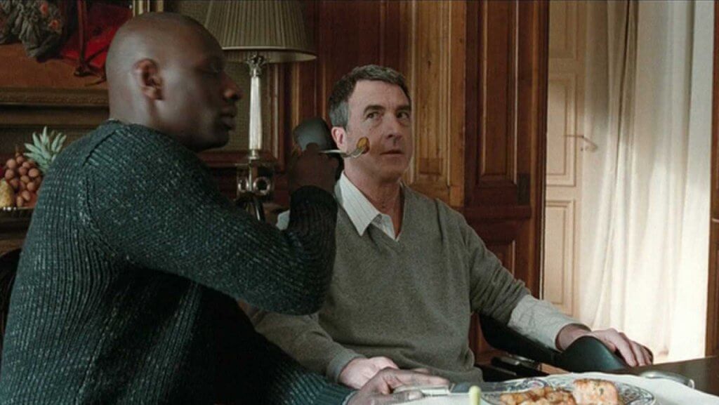 Chico dando de comer a un hombre discapacitado