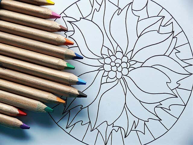 Colored pencils on a paper with a mandala printed on it.