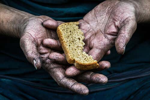 Mano con un trozo de pan de una persona pobre