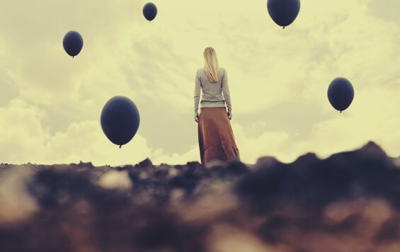 chica envuelta en globos oscuros representando la desesperanza creativa