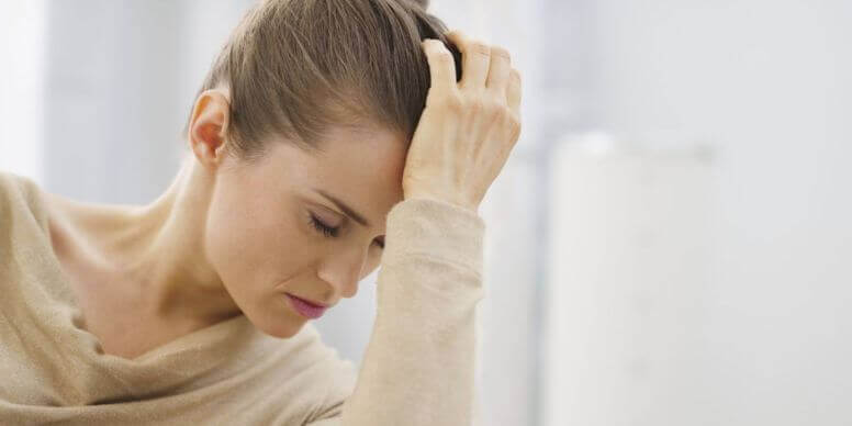 Mujer con una mano en la frente