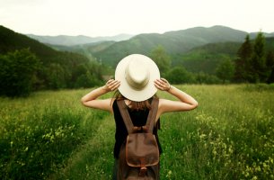 Mujer con sombrero en la montaña para representar a los viajeros incansables