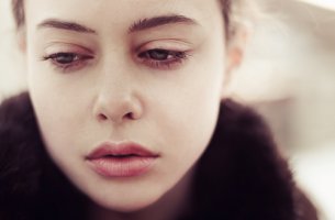 Mujer mirando hacia abajo con cara de tristeza por un recuerdo traumático