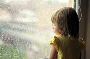 Niña mirando por la ventana