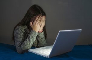 Niña tapándose la cara con miedo por ser víctima de grooming