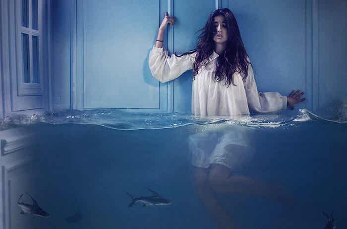 mujer en el agua rodeada de tiburones errados simbolizando el miedo que se disfraza de pereza