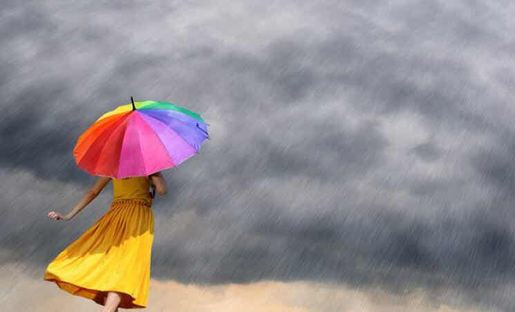 mujer con paraguas de colores afrontando la adversidad