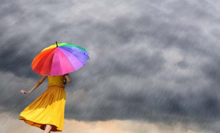 mujer con paraguas de colores afrontando la adversidad