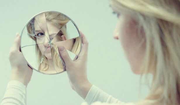 Mujer que sufre violencia psicológica mirándose en un espejo roto