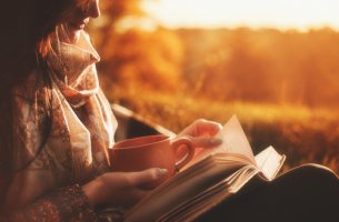 Mujer tomando un café y leyendo un libro