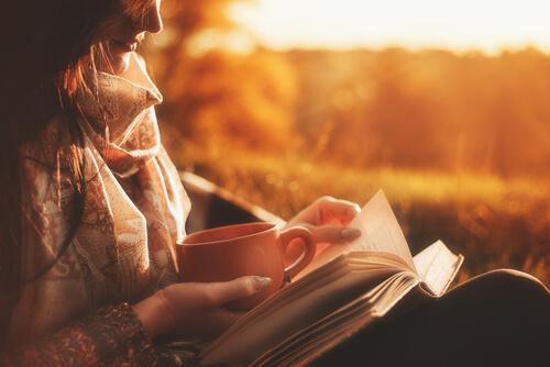 Mujer tomando un café y leyendo un libro