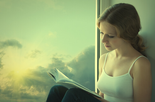 Niña leyendo un libro al lado de una ventana
