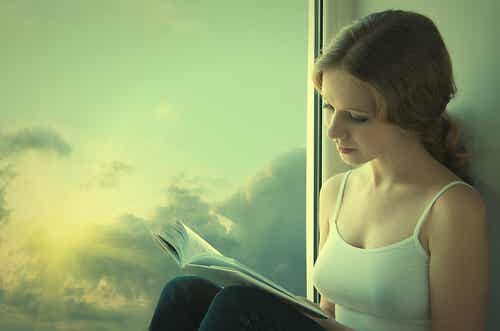 Niña leyendo un libro al lado de una ventana simbolizando los beneficios de la literatura y la poesía