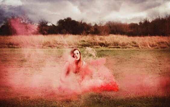 Chica en el campo envuelta en humo rojo