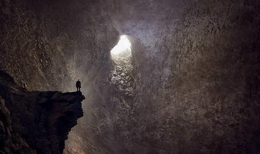 Hombre mirando gruta de salida tras haber tocado fondo
