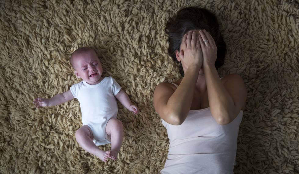 Madre llorando con su hijo al lado