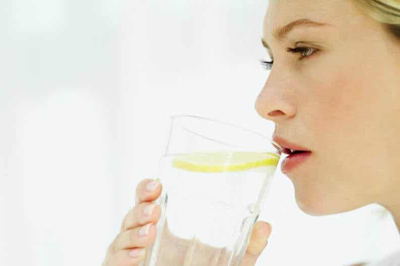 Mujer que bebe agua tibia con limón por las mañanas