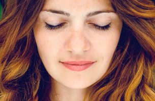 Mujer con los ojos cerrados mientras sonrie