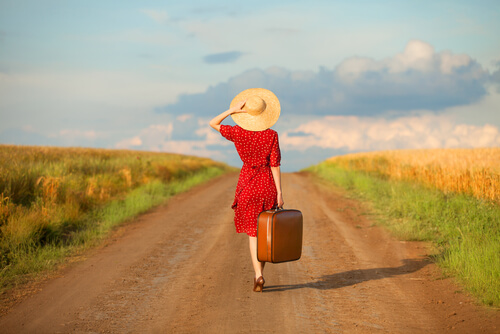 Mujer con maleta por un camino