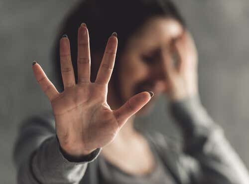 Mujer con palma de la mano abierta con miedo por efecto de la violencia sexual