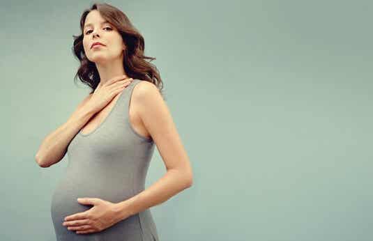 mujer tocándose el cuello simbolizando la tiroides y embarazo