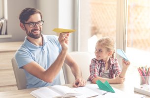 Padre e hija lanzando aviones de papel