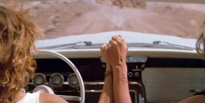 Thelma y Louise agarradas de la mano en el coche