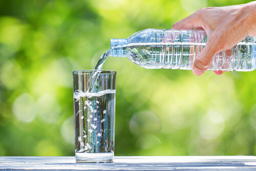 Botella echando agua en un vaso