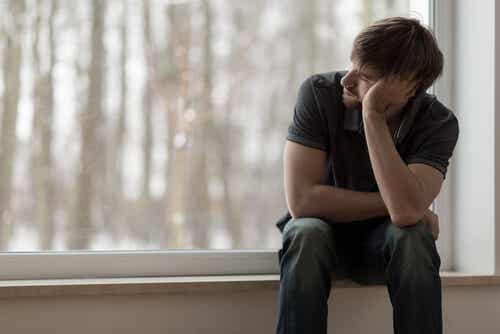 Chico triste sentado en una ventana simbolizando cuando una pareja no entiende nuestra depresión