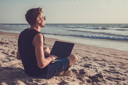 Hombre en la playa con un portatil