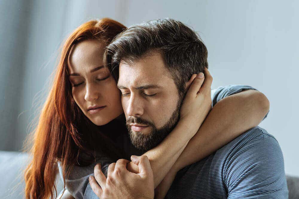 Mujer abrazando a un hombre con los ojos cerrados
