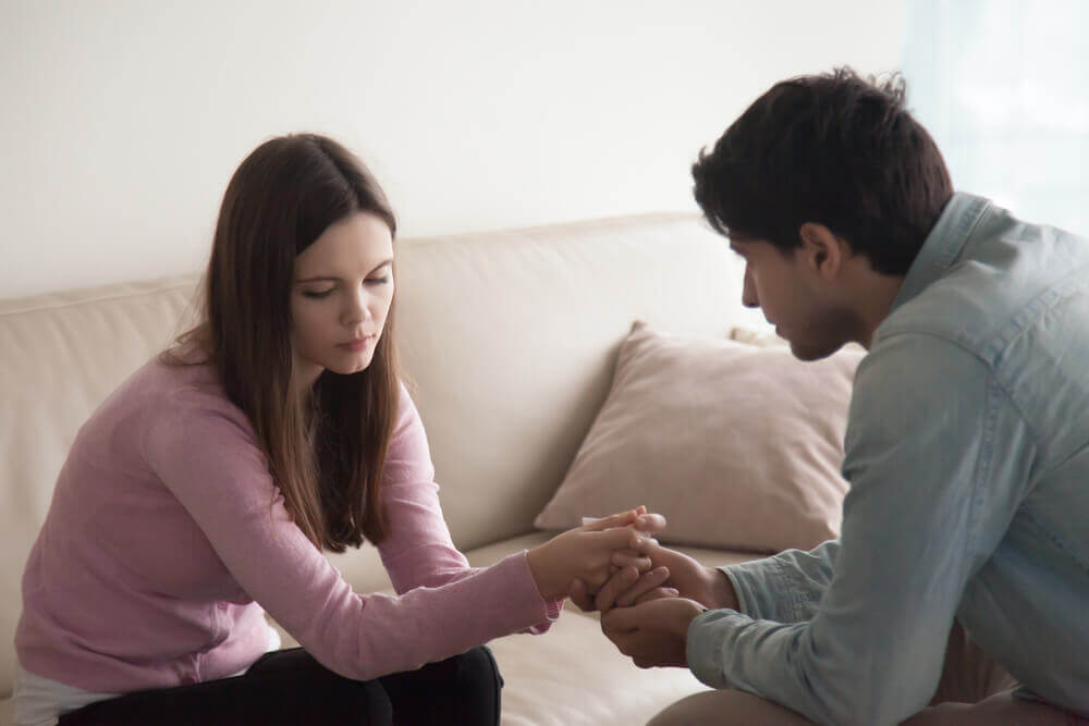 Chico cogiendo la mano de una chica decepcionada por promesas de amor incumplidas